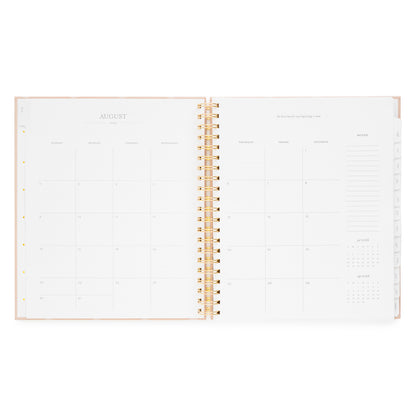 Open spiral planner layout with monthly grid for August 2026 with inspirational quote and notes on the right