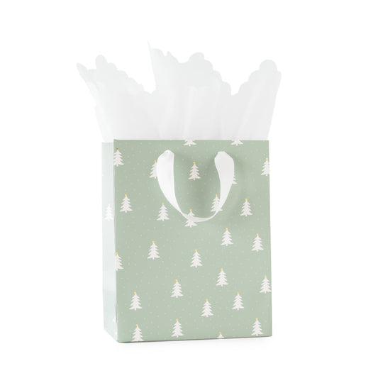 A mint green gift bag with a white pine Christmas tree pattern with gold foil details and white grosgrain ribbon handles, filled with white tissue paper