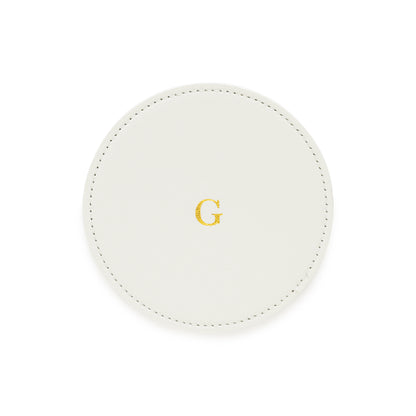 white monogrammed coaster with gold foil g on it