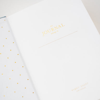 interior page of fabric journal printed in gold foil with this journal belongs to