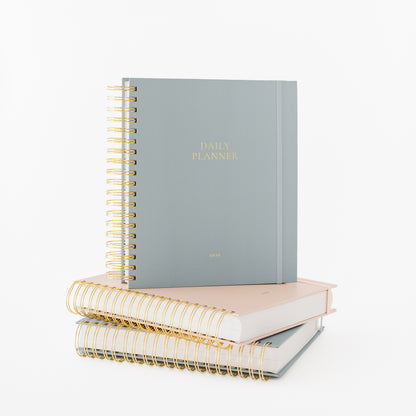 Stack of blue and pink spiral planners with gold wire binding