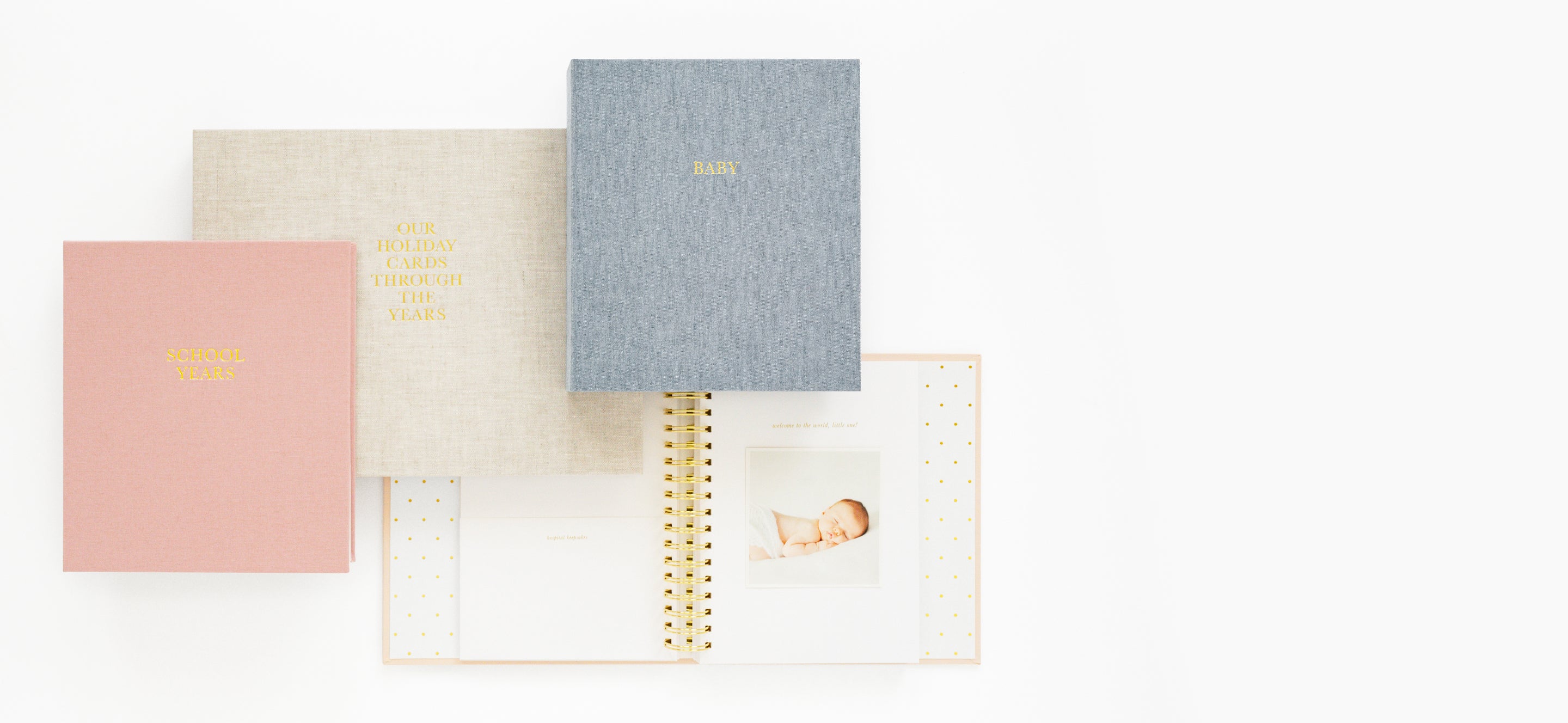 Pink, flax, and blue keepsake memory books on a white surface.
