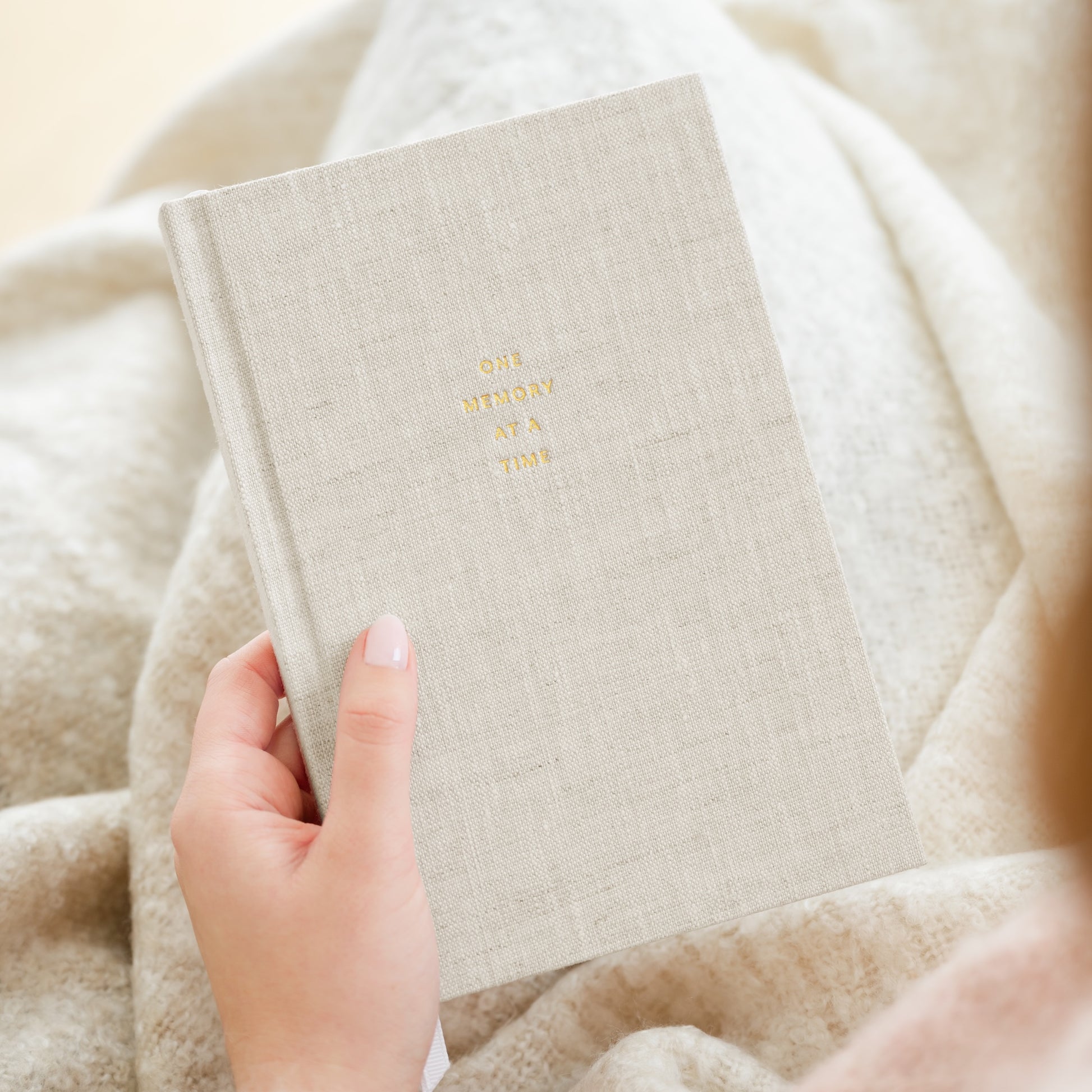 flax fabric one memory at a time book gold foil stamped with one memory at a time in gold on the cover in hand