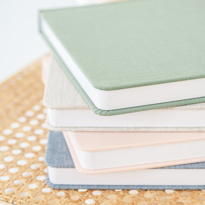 stack of fabric undated planners in green, flax, pale pink and chambray