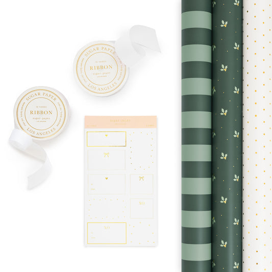 A flat-lay product of gift wrap items including two rolls of ribbon, a sheet of gift stickers, and three rolls of patterned wrapping paper on a clean white background. One roll is a dark green and mint stripe, one is green background with mint green holly and gold dots and a white with gold swiss dot pattern