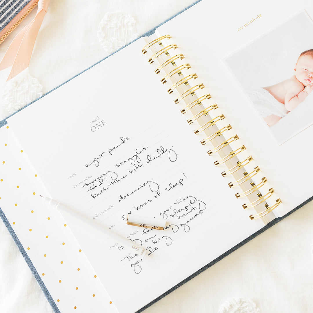 Interior of baby book open to month one with prompts and photo of a baby on other page at "one month old"
