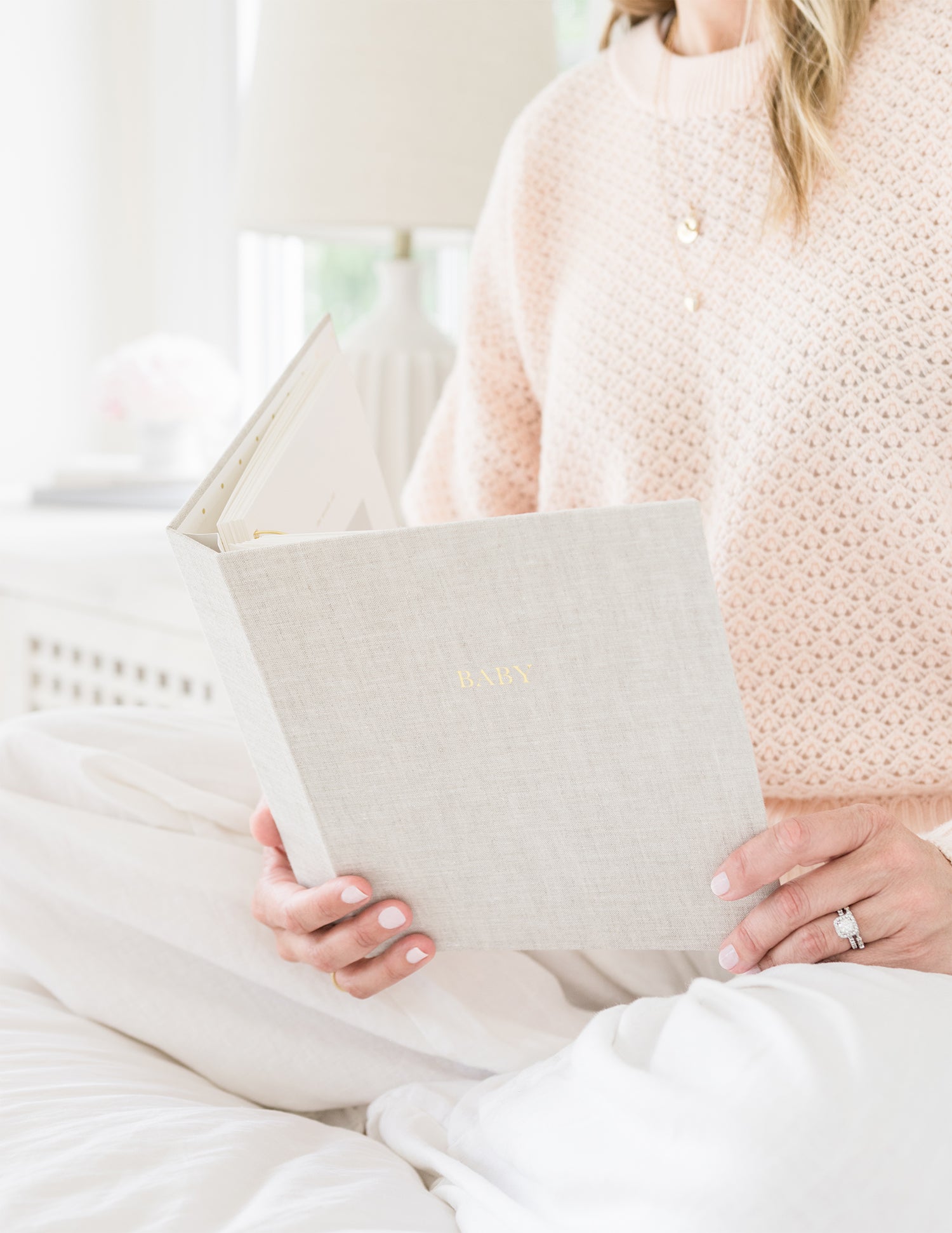 Flax linen baby book in hands sitting on a bed