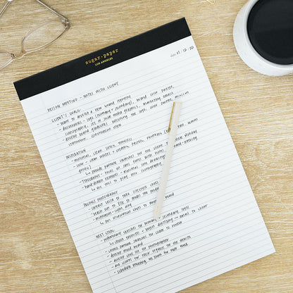 black legal pad on desk with felt pen